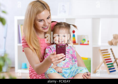 Mère et son petit enfant fille en tenant sur une couverture selfies en maternelle prix Banque D'Images