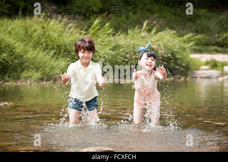 Garçon et une fille jouant dans l'eau du ruisseau jouissant de leurs vacances d'été Banque D'Images