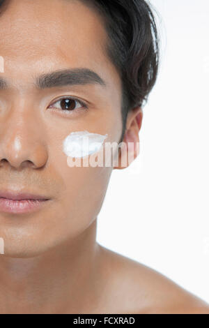 Portrait de jeune homme l'application de lotion sur son visage Banque D'Images