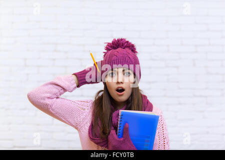 Étourdis attrayant Teenage Girl In Pink Hat Holding Pencil Dossier étudiant choqué Banque D'Images