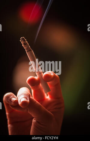 Image en couleur d'une main tenant une cigarette. Banque D'Images