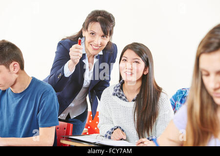 Smiling teacher aide un étudiant pendant un test et lui donne une astuce Banque D'Images