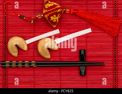 Nouvel an chinois porte-bonheur, fortune cookies et Baguettes en bambou noir sur rouge mat Banque D'Images