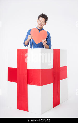 Man holding et montrant une forme de cœur dans une boîte-cadeau avec ruban rouge Banque D'Images