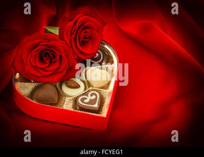 Roses rouges et des bonbons au chocolat en boîte cadeau. Coeur. L'amour. Photo couleur style vintage Banque D'Images