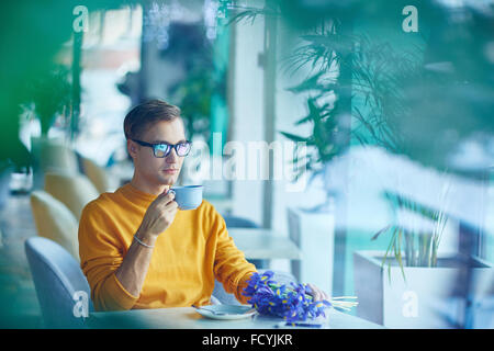 Beau jeune homme de boire du café ou thé dans cafe Banque D'Images