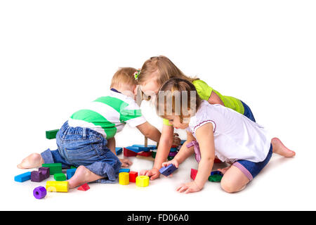 Heureux les enfants jouant avec des blocs de construction isolé sur blanc. Le travail d'équipe, la créativité concept. Banque D'Images