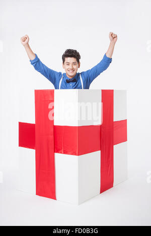 L'homme en chemise bleue placée dans une boîte-cadeau regardant en avant et en mettant ses mains en hauteur Banque D'Images