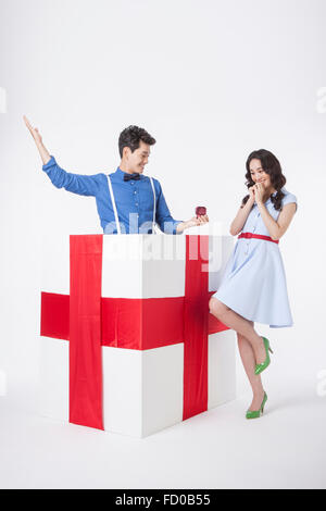 L'homme en chemise bleue placée dans une boîte-cadeau donnant un anneau à une femme dans le style rétro et d'être surpris Banque D'Images