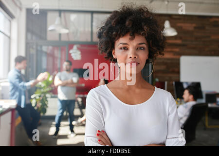 Portrait of woman standing in busy creative office looking at camera. Professionnel de la création féminine attrayante dans design studio. Banque D'Images