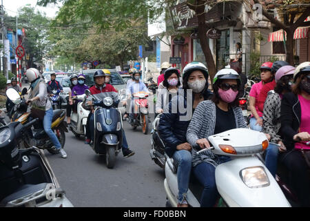 Des scooters avec cavaliers, certains portant des masques, dans une rue animée de Hanoi, Vietnam Banque D'Images