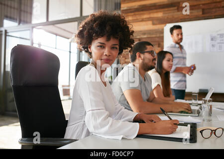 Portrait of businesswoman sitting at une présentation d'affaires avec des collègues dans la salle. Femme africaine avec un collègue Banque D'Images