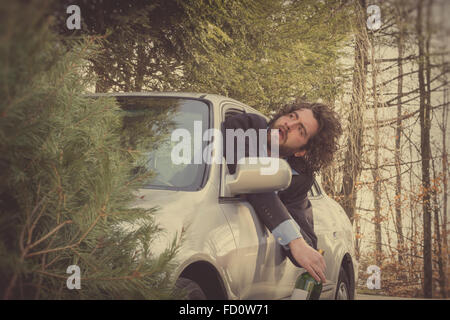 L'homme ivre qui dépassent de la fenêtre de bouteille de vin après conduite accident de voiture Banque D'Images
