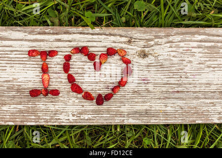 Les fraises sont énoncés dans les lettres sur un fond d'herbe verte et de sélection. Banque D'Images