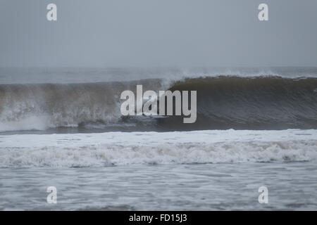 Courses de surfer sur toute la ligne et sur le point de rentrer dans un tube. Photographié à Rockaway Beach, New York le 29 décembre 2015. Banque D'Images