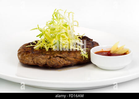 Des portions de juteux épais succulent steak poêlé, servi avec une sauce tomate sur une plaque blanche Banque D'Images