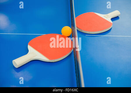 Raquettes de ping-pong et la bille et net sur une table ping-pong bleu Banque D'Images