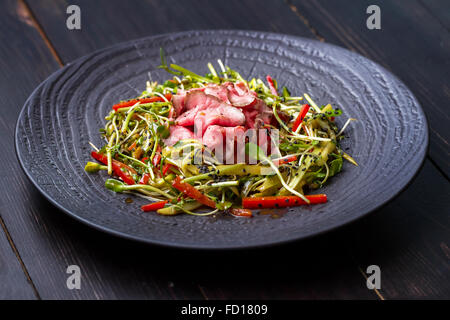 Salade authentique avec bacon poivron rouge frais, les germes, de sésame et d'huile d'olive sur une plaque noire. Matin, l'éclairage atmosphérique Banque D'Images