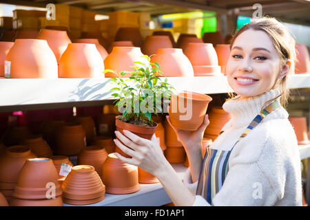 Heureux jolie jeune femme acheter nouveau jardinier pot pour son usine à la boutique Banque D'Images