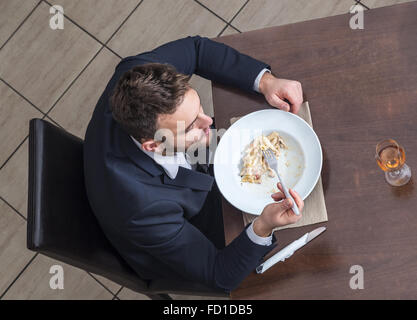 Vue de dessus d'un jeune businessman eating pâtes italiennes dans un restaurant. Banque D'Images