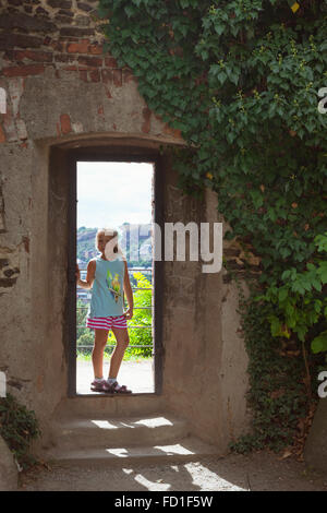 PRAGUE, RÉPUBLIQUE TCHÈQUE - 28 août 2015 : Une jeune fille se tient dans l'embrasure de la porte, le mur est recouvert de charlatan de raisin. Vysehrad Banque D'Images