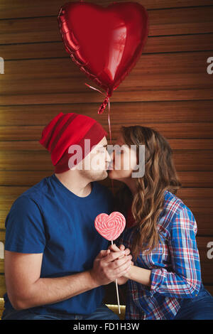 Amorous valentines avec ballon en forme de coeur et sucker kissing in cafe Banque D'Images