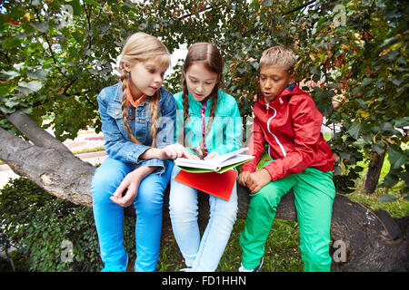 Friendly schoolkids livre de lecture en plein air Banque D'Images