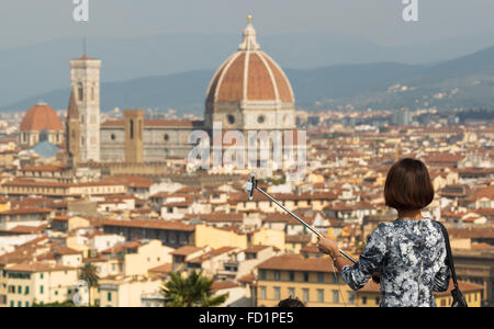 Une jeune femme se prépare à prendre un en selfies Piazzale Michelangelo, Florence, Toscane, Italie. Banque D'Images