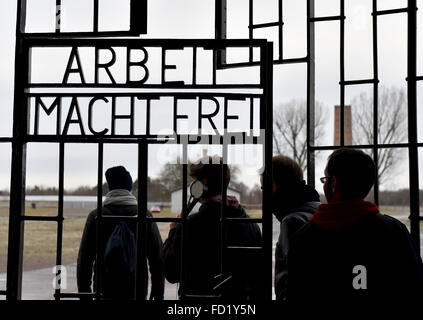 Oranienburg, Allemagne. 17 Jan, 2016. Visiteurs franchissent la porte de l'ancien camp de concentration de Sachsenhausen, qui portent les mots "Arbeit macht frei" (le travail des ensembles vous free'), dans Oranienburg, Allemagne, 17 janvier 2016. Les victimes du national-socialisme ont commémoré aujourd'hui à de nombreux endroits à l'échelle nationale. Photo : BERND SETTNIK/dpa/Alamy Live News Banque D'Images
