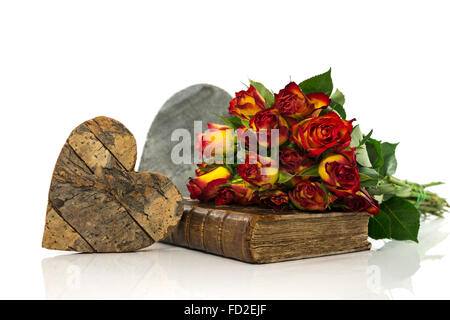 Vieux livre avec des roses rouges et jaunes en bois et carte de saint valentin coeur Banque D'Images