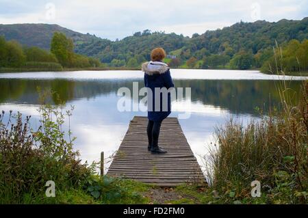 Parc National de Lake District. Woman standing on jetty. Grasmere, Lake District, Cumbria, Angleterre, Royaume-Uni. Banque D'Images