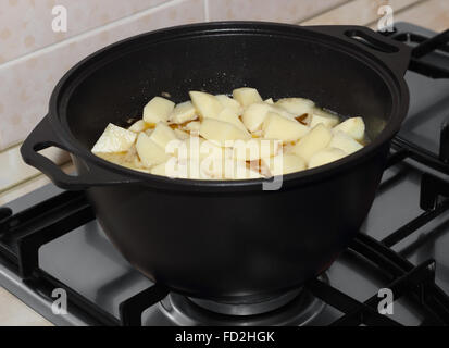 Les pommes de terre coupées en dés à l'étuvée dans le black metal pot sur la cuisinière à gaz Banque D'Images