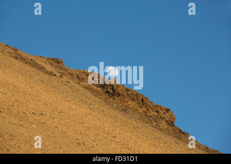 La lune se lève au-dessus d'une pente rocheuse du Mont Teide dans le Parc National du Teide sur Tenerife, Espagne. La montagne est le plus élevé de l'Espagne. Banque D'Images