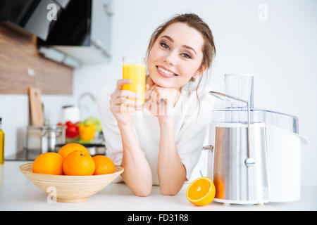 Belle jeune femme assis et boire du jus d'orange Banque D'Images