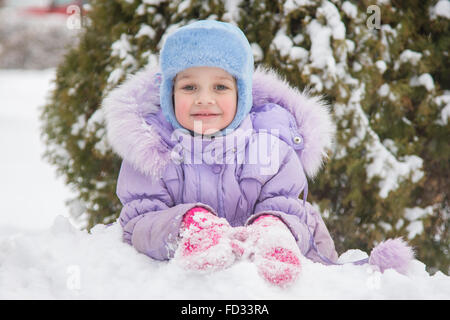 Fille de cinq ans se situe sur la neige Neige Neige arbres contre un arrière-plan Banque D'Images