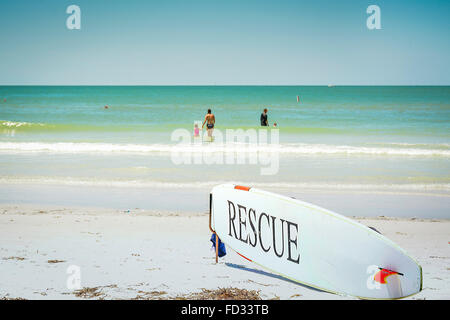 Une planche de sauvetage à l'avant de la station de sauvetage avec des personnes jouant dans les eaux peu profondes bleu Siesta Key Beach Banque D'Images