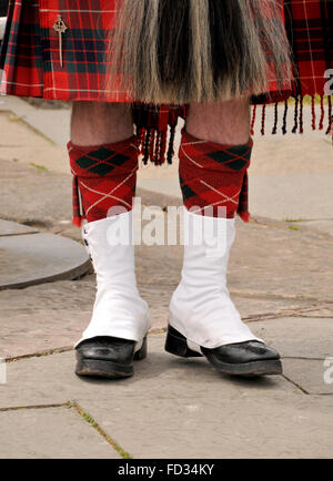 Les jambes et les chaussures d'un homme habillé en écossais permanent un kilt en tartan rouge vérifié. Banque D'Images