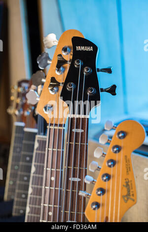 Guitares électriques, guitares acoustiques et basses électriques guitares sur un rack dans un studio montrant le cou, fretboard et cordes Banque D'Images