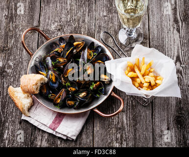 Moules, frites et vin sur fond de bois Banque D'Images