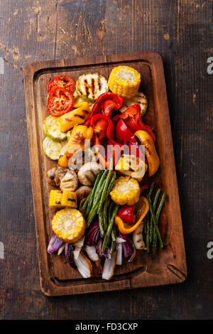 Légumes grillés sur une planche à découper sur fond de bois foncé Banque D'Images