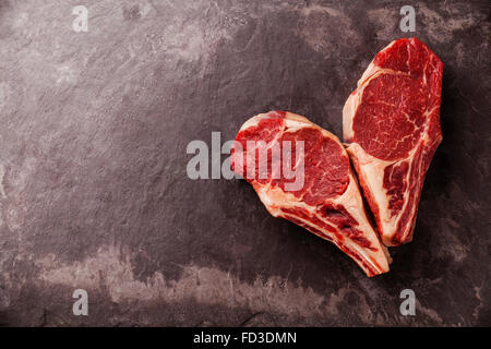 Forme de coeur matières la viande fraîche Ribeye Steak sur l'os sur fond ardoise Banque D'Images