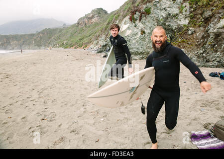 Deux surfeurs goof autour sur la plage avant de sauter dans l'eau pour attraper des vagues à Big Sur, en Californie. Banque D'Images