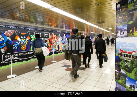 Les piétons devant une immense murale Dragon Quest fait en blocs Lego Le 27 janvier 2016 à Tokyo, Japon. La fresque fait partie d'une promotion à la gare de Shinjuku pour fêter la sortie de nouveau le jeu Dragon Quest les constructeurs. La murale a été faite de 80 mètres avec 180 000 les blocs de Lego et les fans seront autorisés à supprimer des blocs à partir du 28 janvier pour révéler un secret derrière l'affiche. Certains blocs contiennent aussi des codes QR permettant aux fans d'accéder à des contenus exclusifs. © Rodrigo Reyes Marin/AFLO/Alamy Live News Banque D'Images