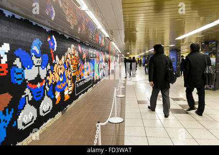 Les piétons devant une immense murale Dragon Quest fait en blocs Lego Le 27 janvier 2016 à Tokyo, Japon. La fresque fait partie d'une promotion à la gare de Shinjuku pour fêter la sortie de nouveau le jeu Dragon Quest les constructeurs. La murale a été faite de 80 mètres avec 180 000 les blocs de Lego et les fans seront autorisés à supprimer des blocs à partir du 28 janvier pour révéler un secret derrière l'affiche. Certains blocs contiennent aussi des codes QR permettant aux fans d'accéder à des contenus exclusifs. © Rodrigo Reyes Marin/AFLO/Alamy Live News Banque D'Images