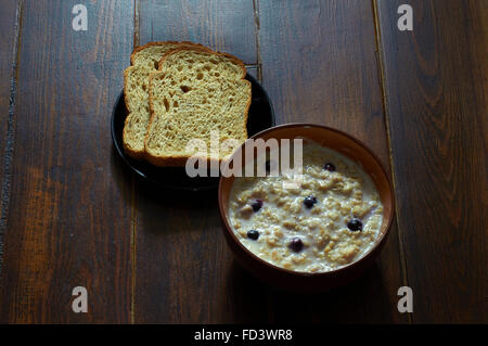 Le petit-déjeuner avec du porridge d'avoine avec des baies et des tranches de pain Banque D'Images