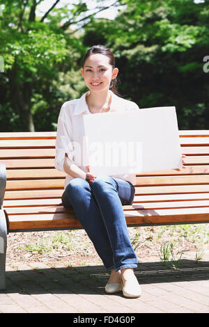 Jolie femme japonaise dans un parc de la ville Banque D'Images