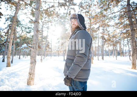 Portrait of attractive young man in vêtements chauds debout dans winter park Banque D'Images