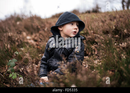 Little Boy wearing hood assis dans la nature Banque D'Images