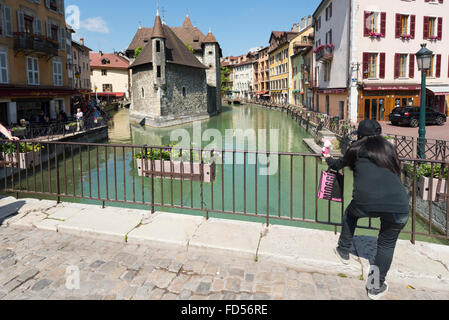 Femme Asiatique de prendre une photo d'un jouet en peluche sur un pont de la vieille ville d'Annecy en face de l'historique Palais de l'Isle Banque D'Images