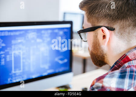 Gros plan du jeune homme à lunettes avec des plans sur ordinateur barbe Banque D'Images